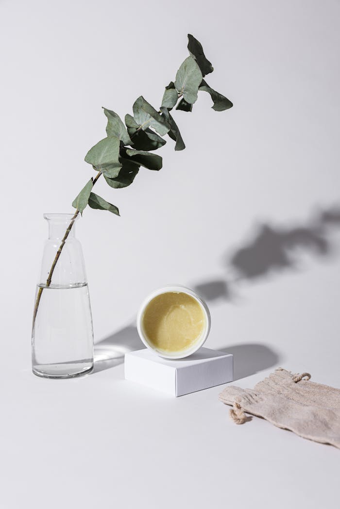 The Art of Drawing Readers In: Your attractive post title goes here Minimalist setup featuring skincare product, eucalyptus in glass vase, and cotton bag.