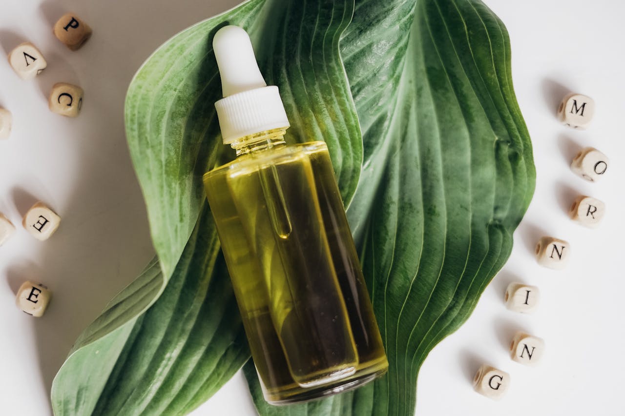 A bottle of natural skincare oil placed on green leaves with letter blocks spelling out 'morning'.